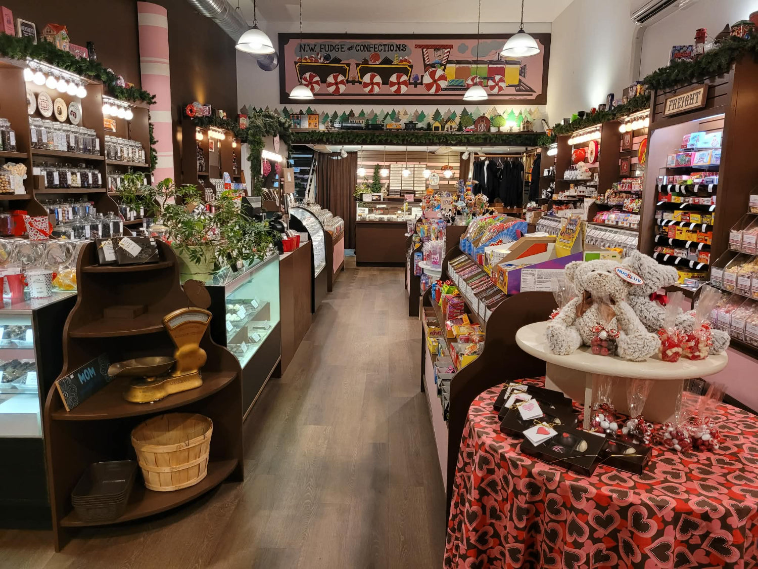 Interior of a store with shelves, display cases, and a table with teddy bears and candy.