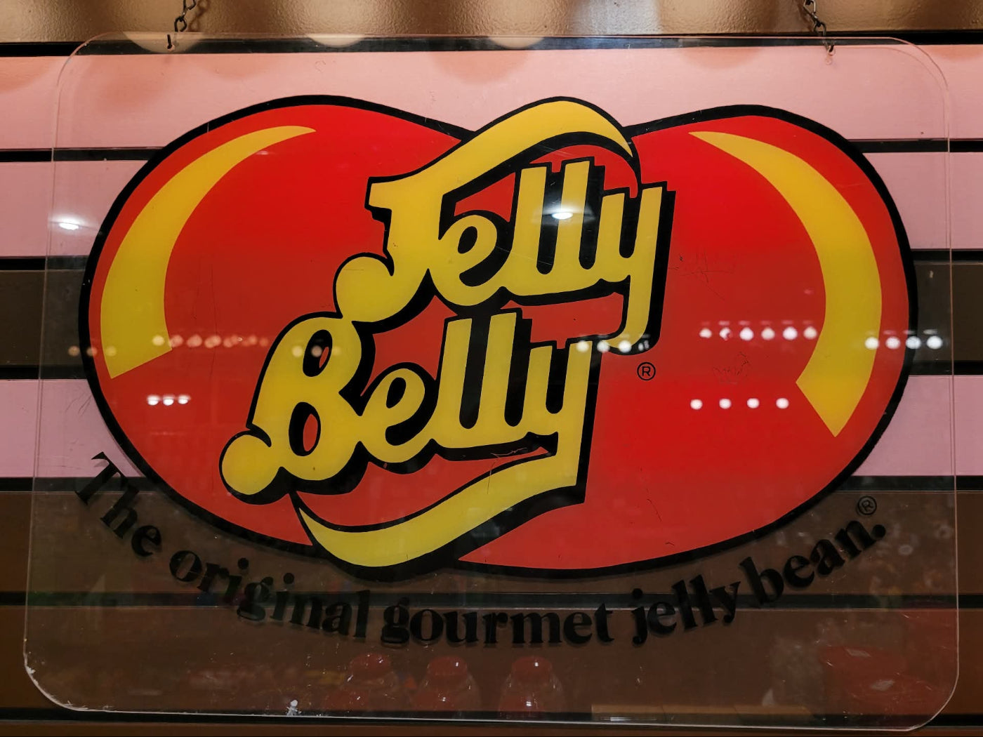 Jelly Belly logo on a red bean-shaped background with a pink and brown striped border.